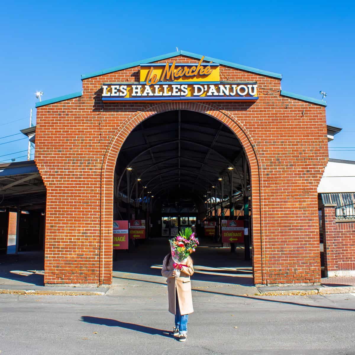 Person holding a colourful bouquet in front of Les Halles d’Anjou in Montreal