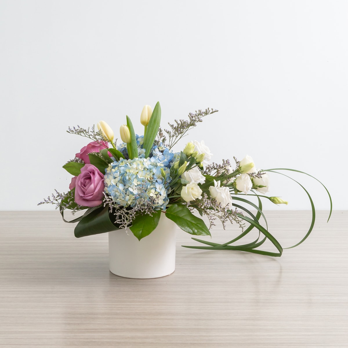 Lizzy in blue arrangement with blue hydrangea, cool water roses, and white lisianthus