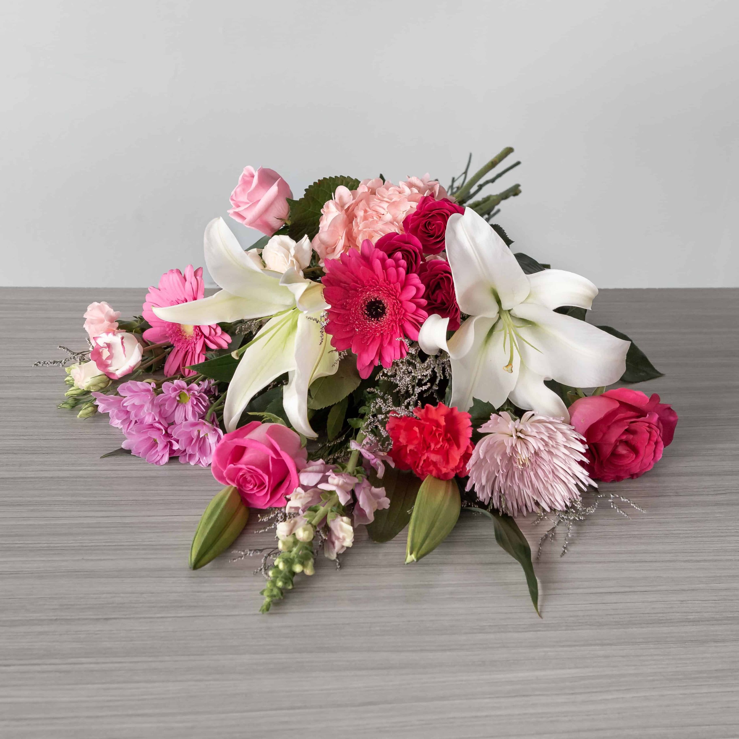 Mother’s Day Elegance hand-tied bouquet with lilies, roses and pink flowers displayed horizontally
