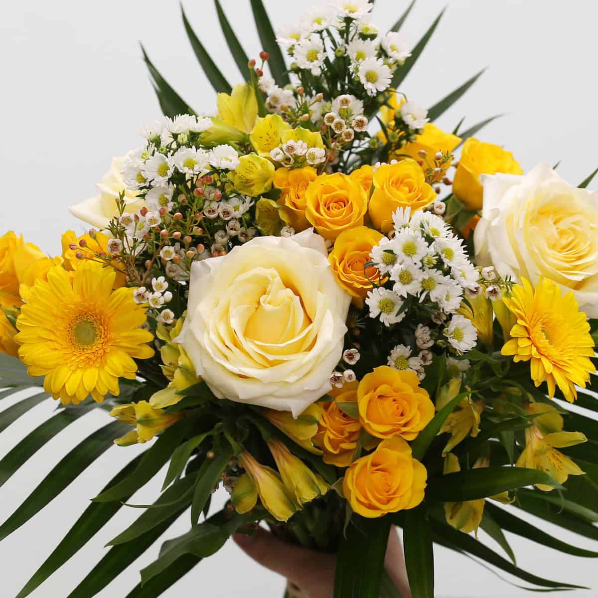 Golden Hour summer bouquet featuring white roses, yellow spray roses, mini gerberas, asters, alstroemeria, and tropical greenery.