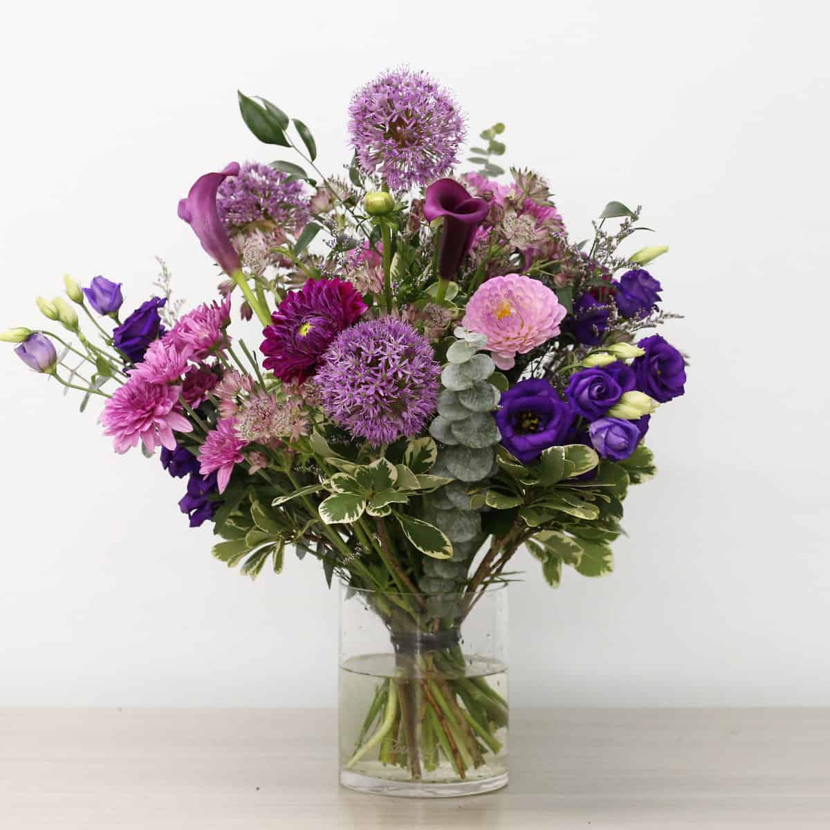 Summer Amethyst floral arrangement with purple flowers in a clear glass vase