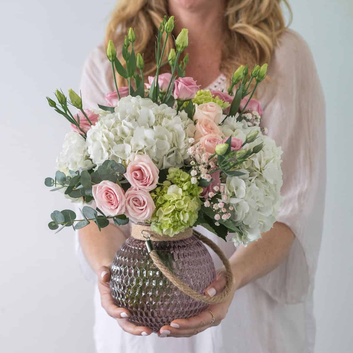 Woman holding the Alexis floral arrangement with blush roses and white hydrangeas
