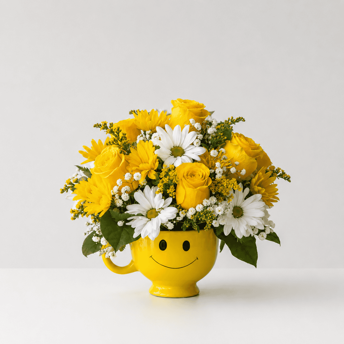 Be Happy Smile in a Cup Bouquet featuring yellow roses, white and yellow daisies in a yellow smiley face mug.