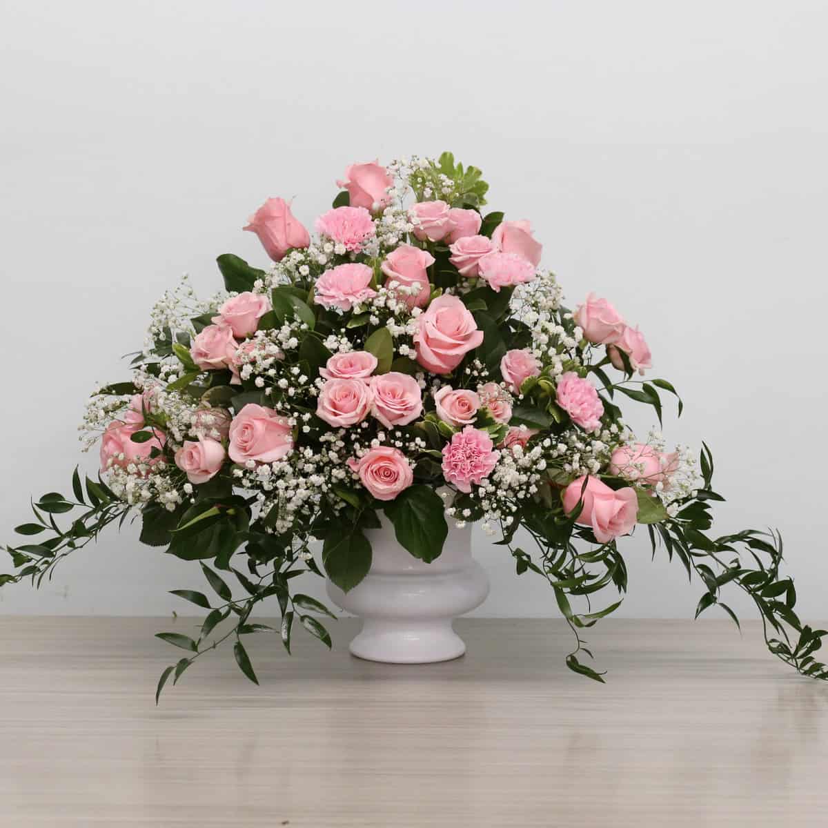 Deepest Sympathy Arrangement in soft pink flowers displayed in a ceramic urn.