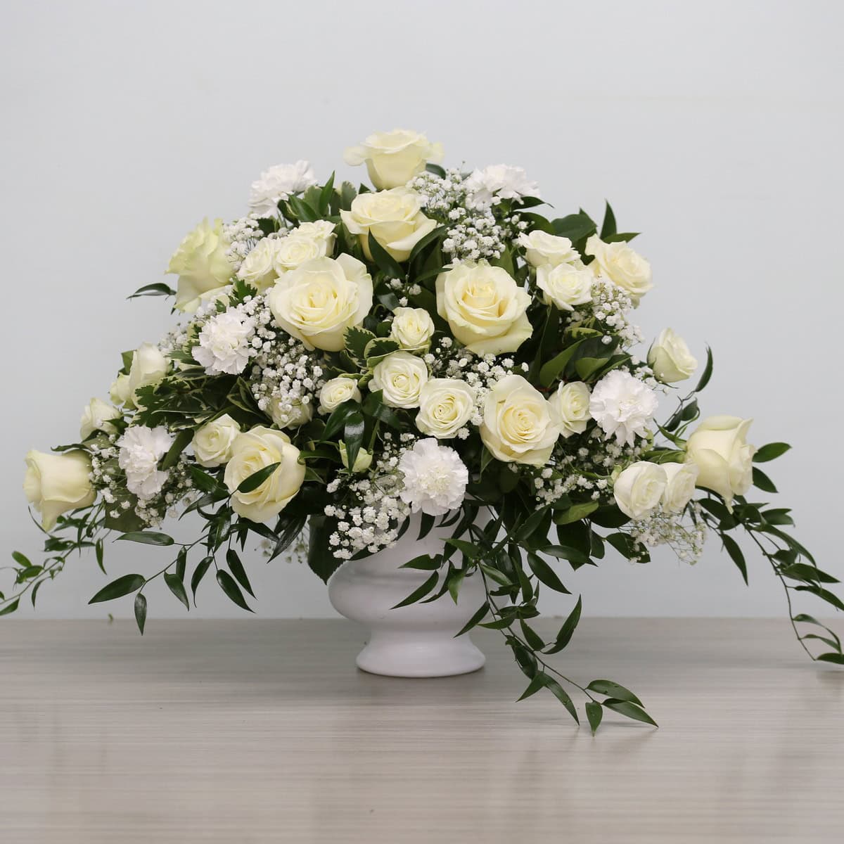 White Deepest Sympathy Arrangement in ceramic urn for funeral service.