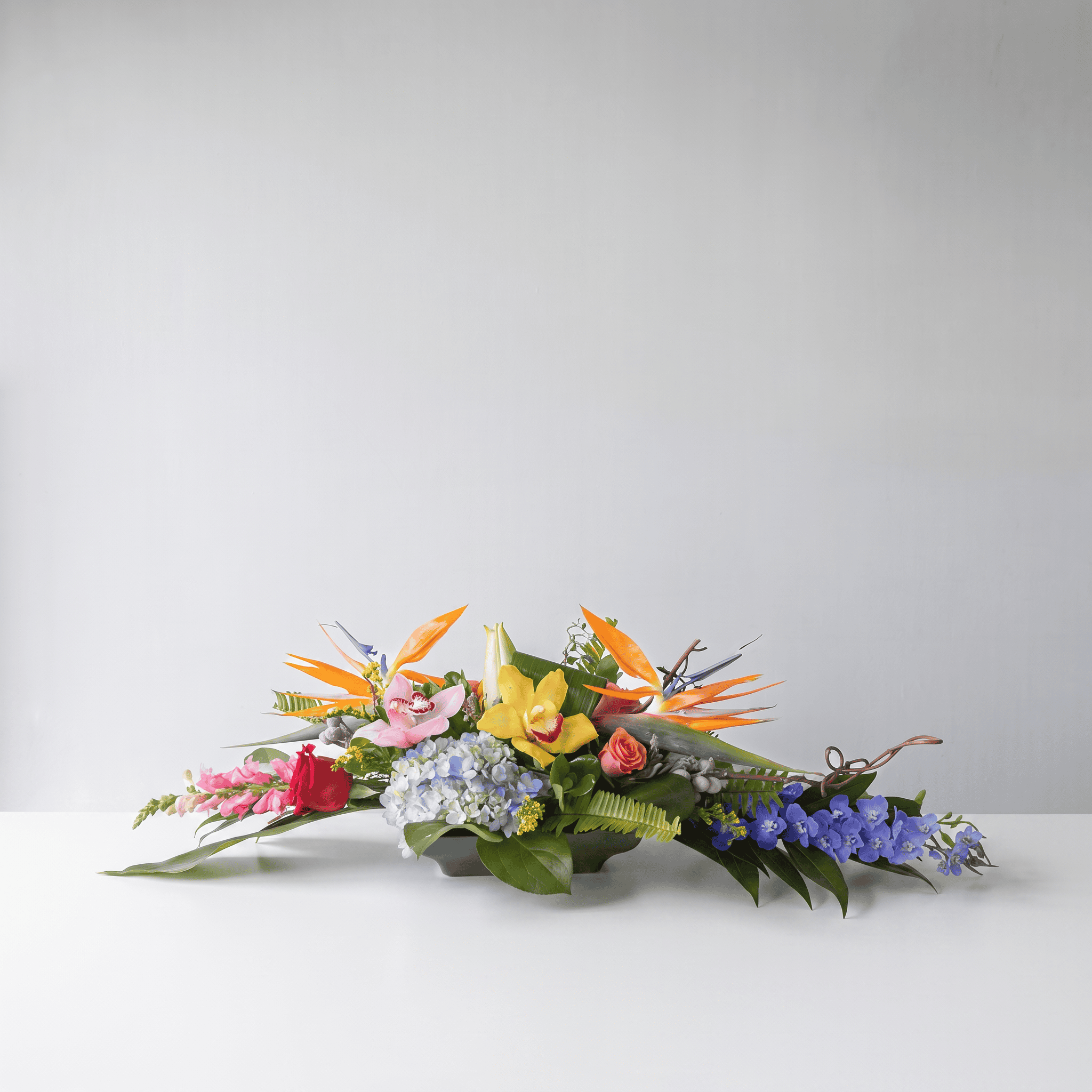 Deluxe Exotic Oval Centerpiece with orchids, birds of paradise, lilies, hydrangea and tropical greenery.