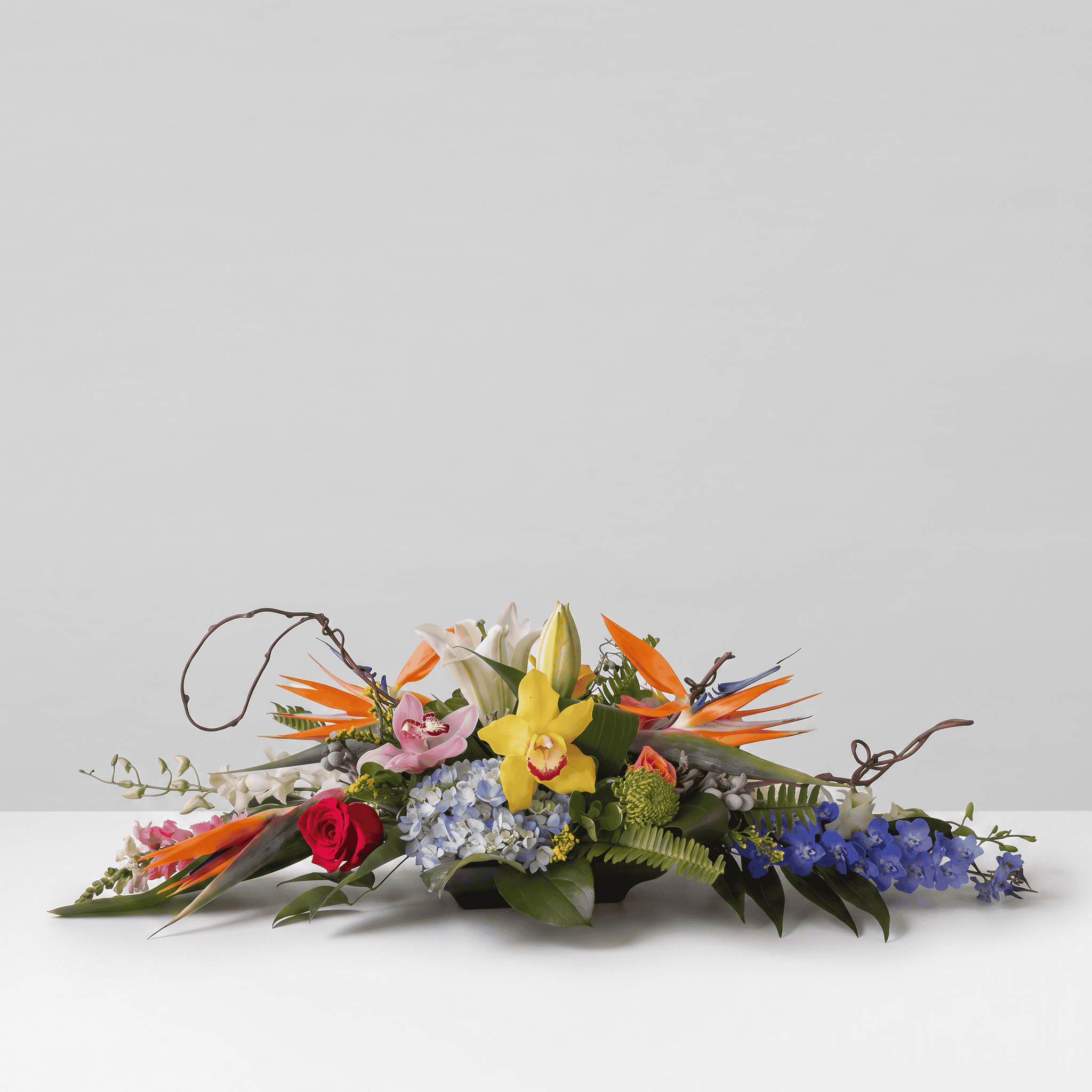Premium Exotic Oval Centerpiece featuring birds of paradise, orchids, lilies, hydrangea and tropical flowers arranged in a low oval design.