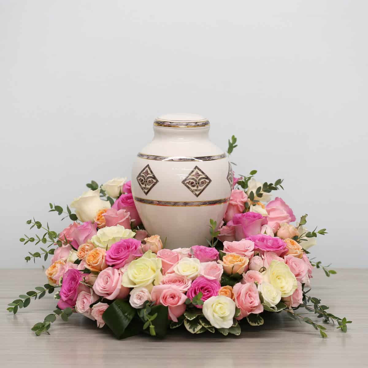 Garden of Roses urn arrangement with pink, blush, and white roses surrounding a cremation urn for a memorial service.