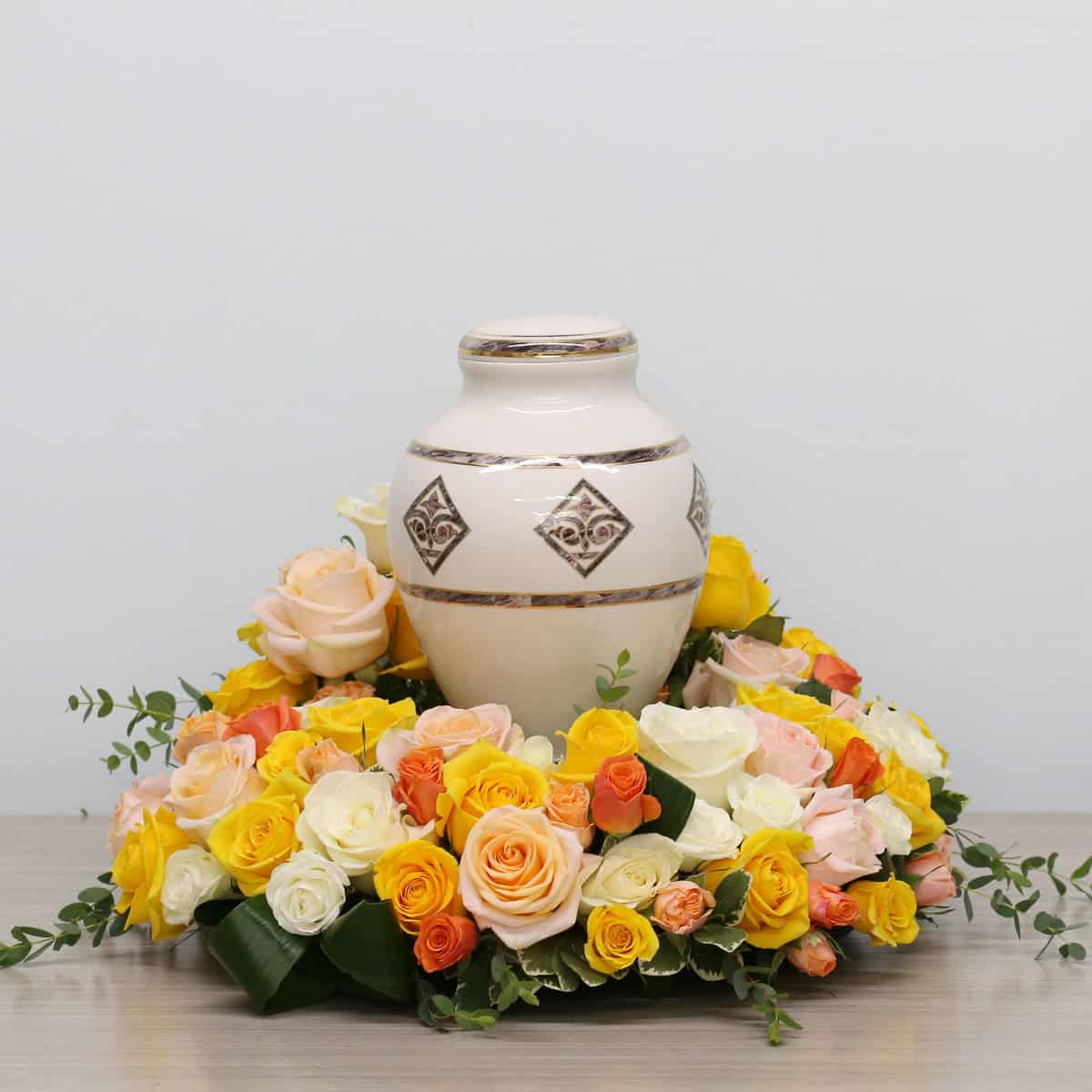 Garden of Roses urn arrangement featuring white, peach, and yellow roses surrounding a cremation urn for a funeral or celebration of life.