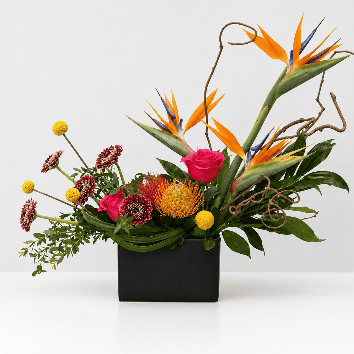 Mango Fusion tropical flower arrangement featuring Birds of Paradise, pincushion proteas, hot pink roses, Craspedia and tropical greenery.