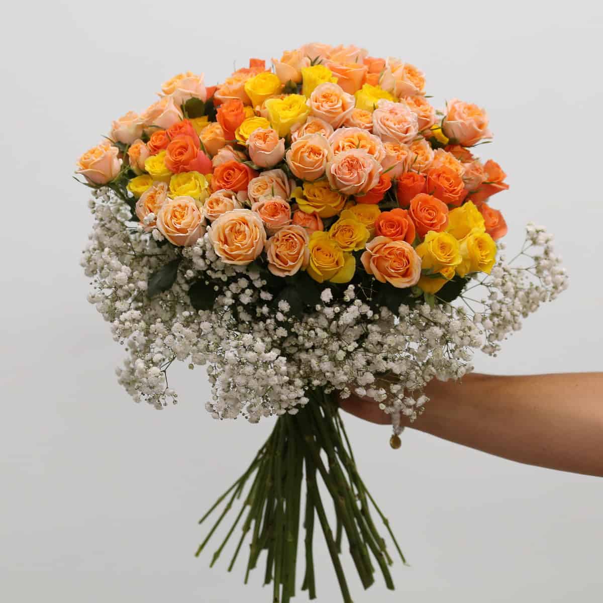 Deluxe Peach Romance hand-tied bouquet with peach, orange and yellow spray roses surrounded by baby's breath.