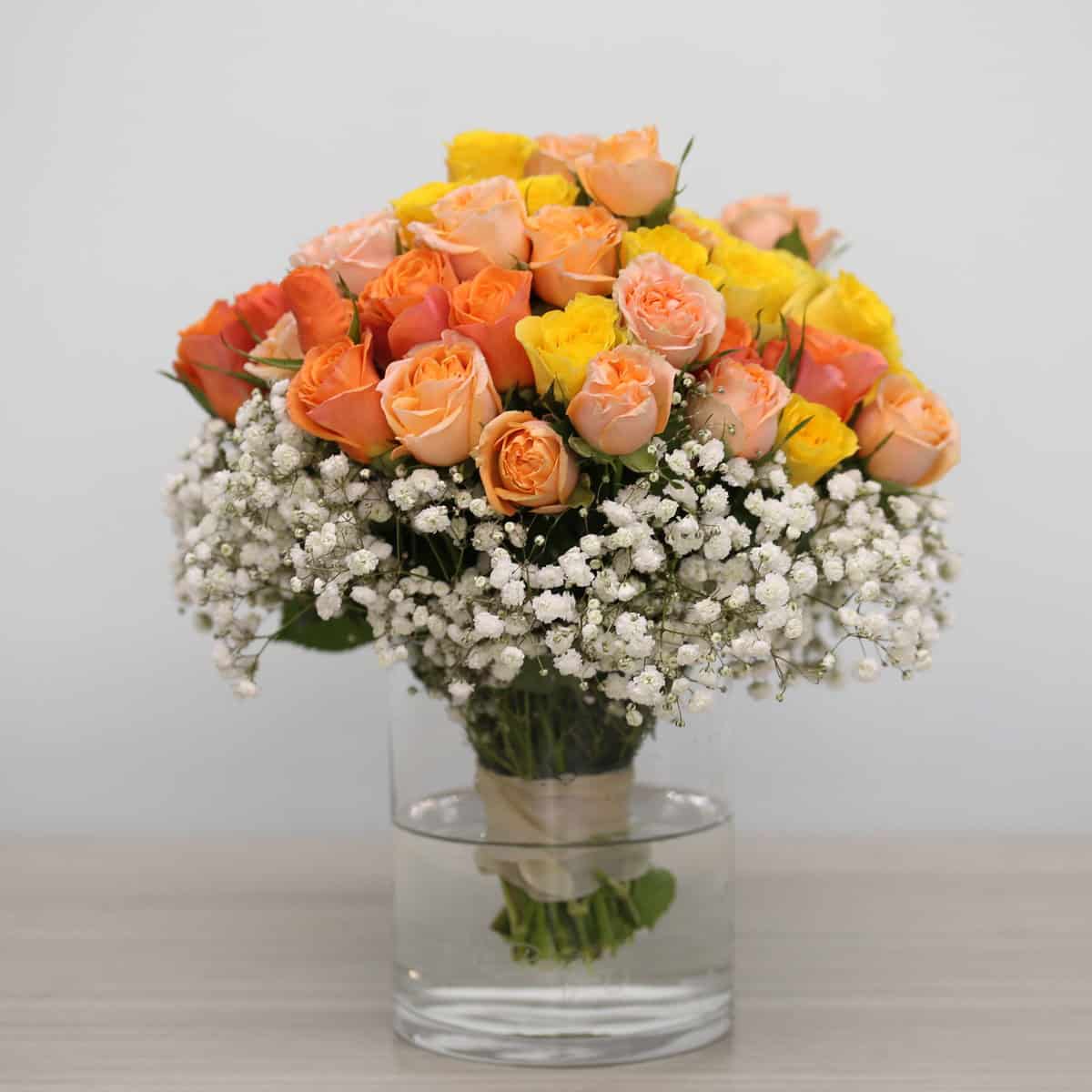 Standard Peach Romance spray rose arrangement in a clear glass vase with baby's breath.