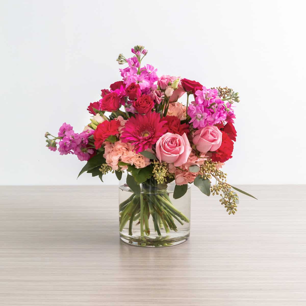 Rear view of the Pink Flamingo flower arrangement featuring pink hydrangea, roses, gerbera daisies, stock and eucalyptus in a glass vase.