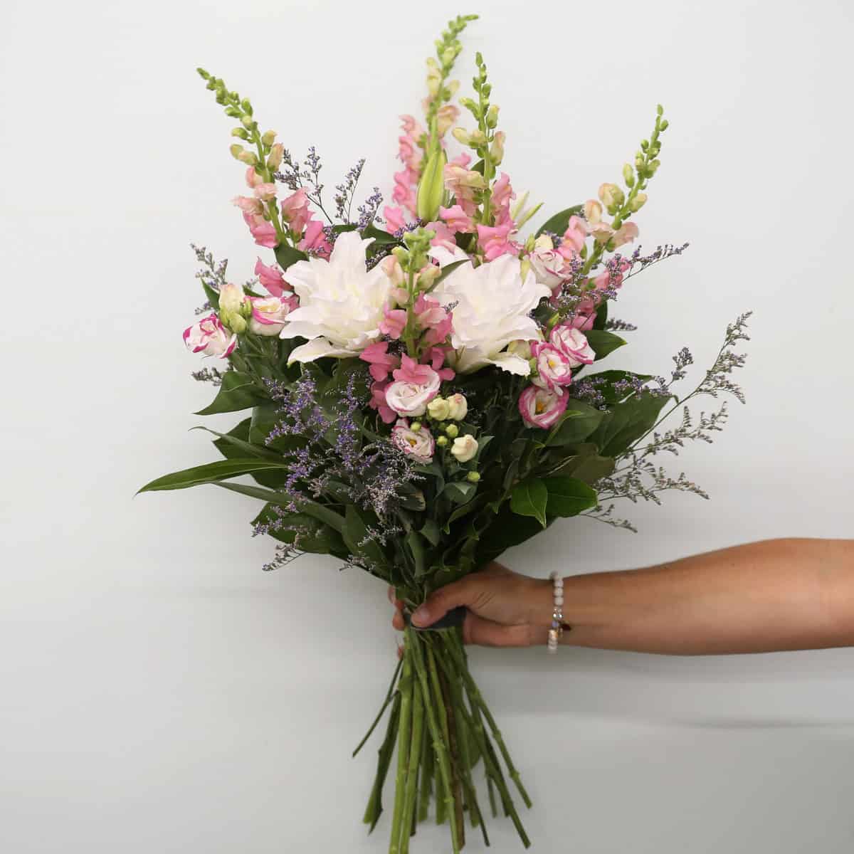 Hand-tied Rosalie bouquet with fragrant RoseLilies, pink snapdragons, pink-rimmed lisianthus and purple caspia.