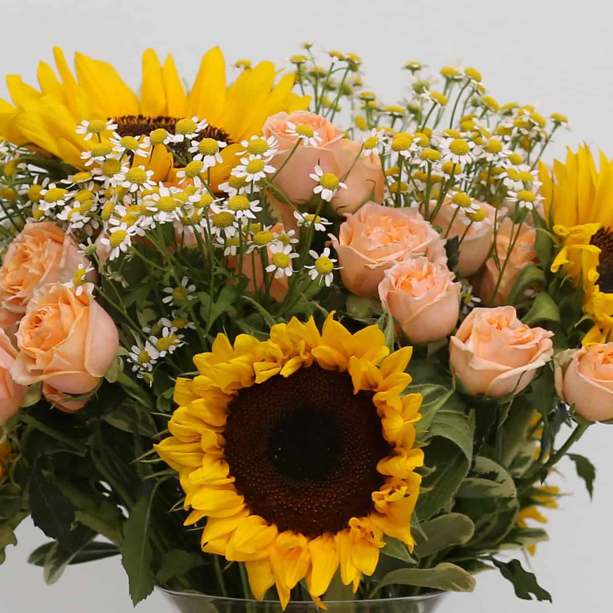 Close-up of the Sunrise Bouquet highlighting sunflowers, peach spray roses and delicate chamomile flowers.