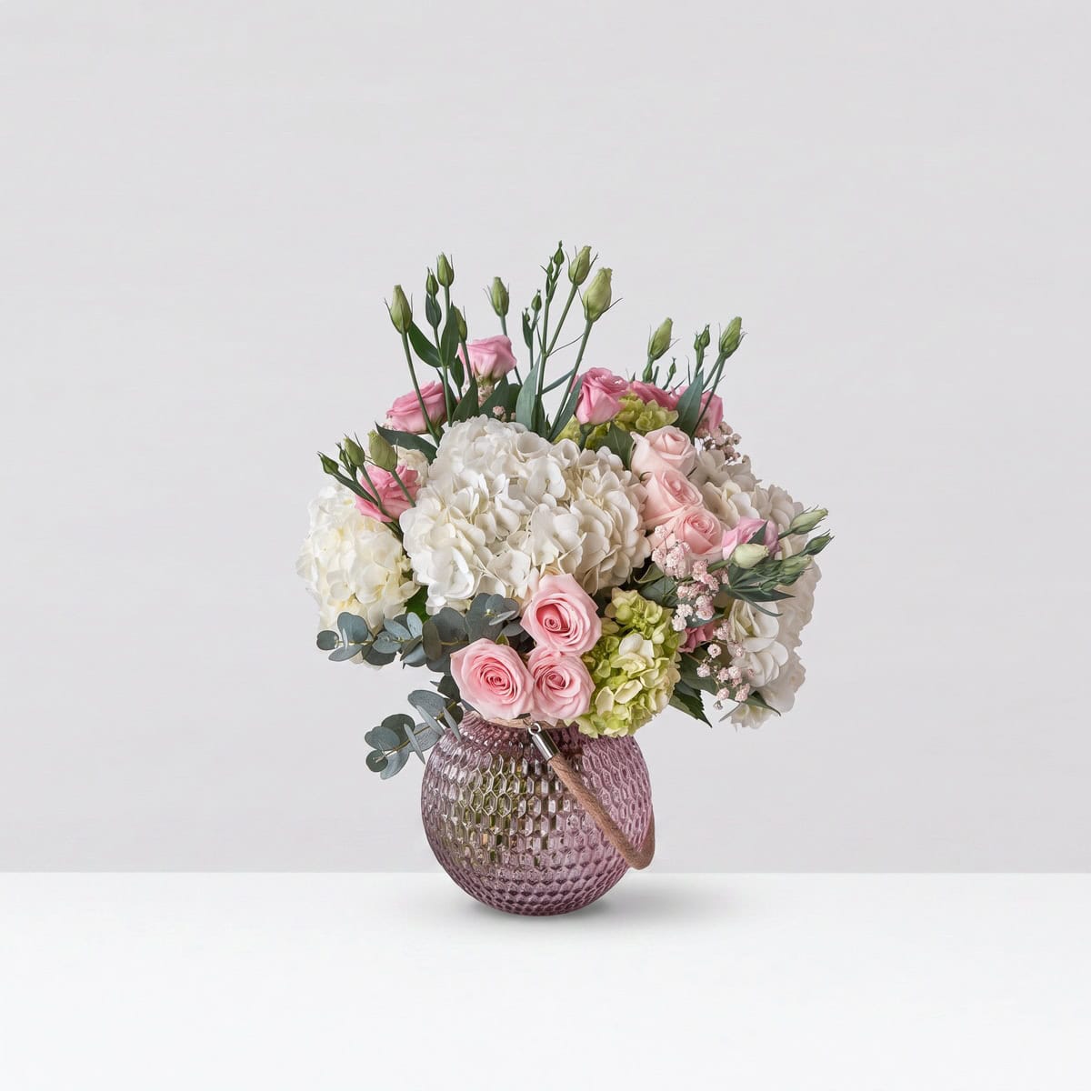 Alexis floral arrangement with blush roses, white hydrangeas, pink lisianthus and eucalyptus in a mauve glass vase