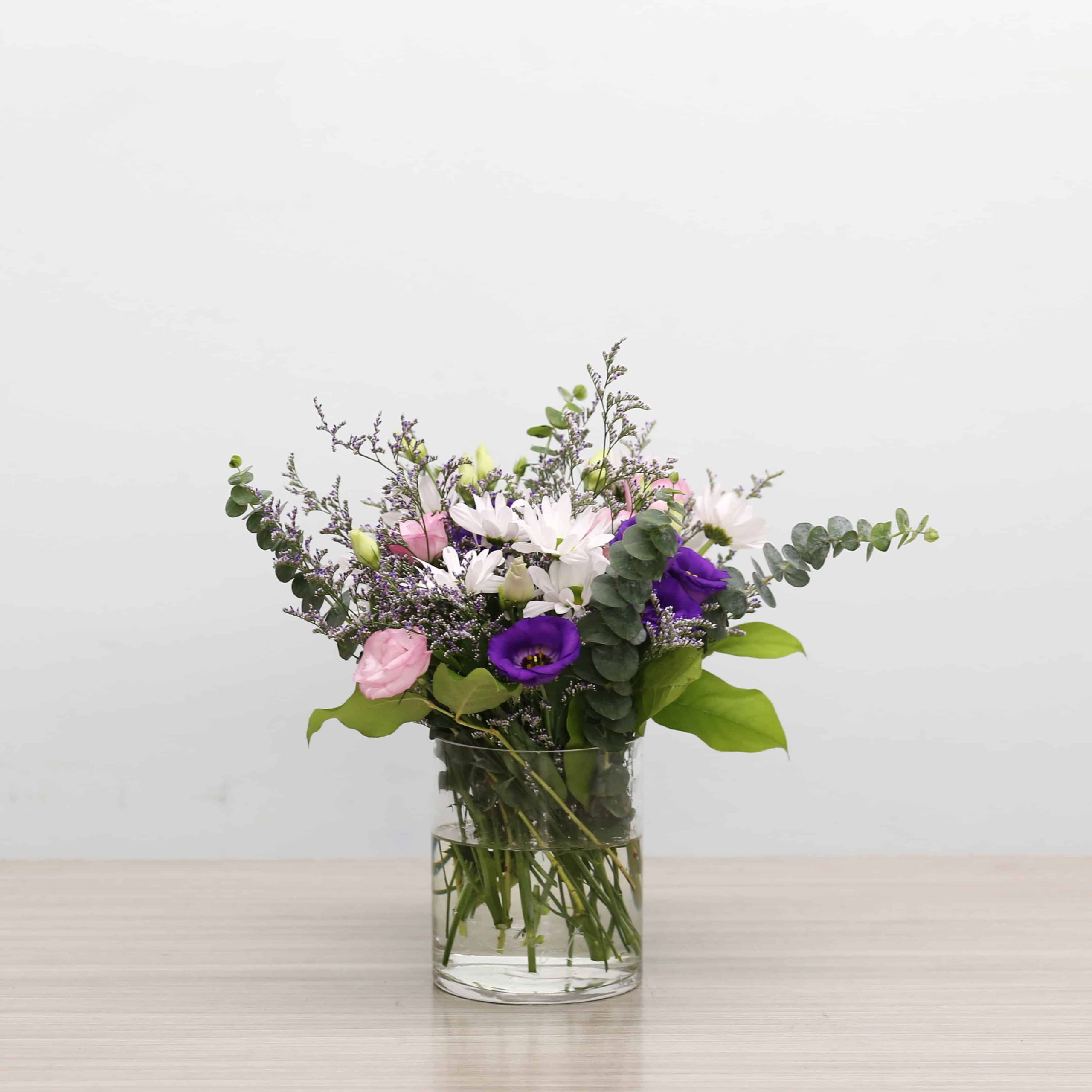 Ariana Standard flower arrangement in glass vase with daisies, pink and purple lisianthus, caspia and eucalyptus