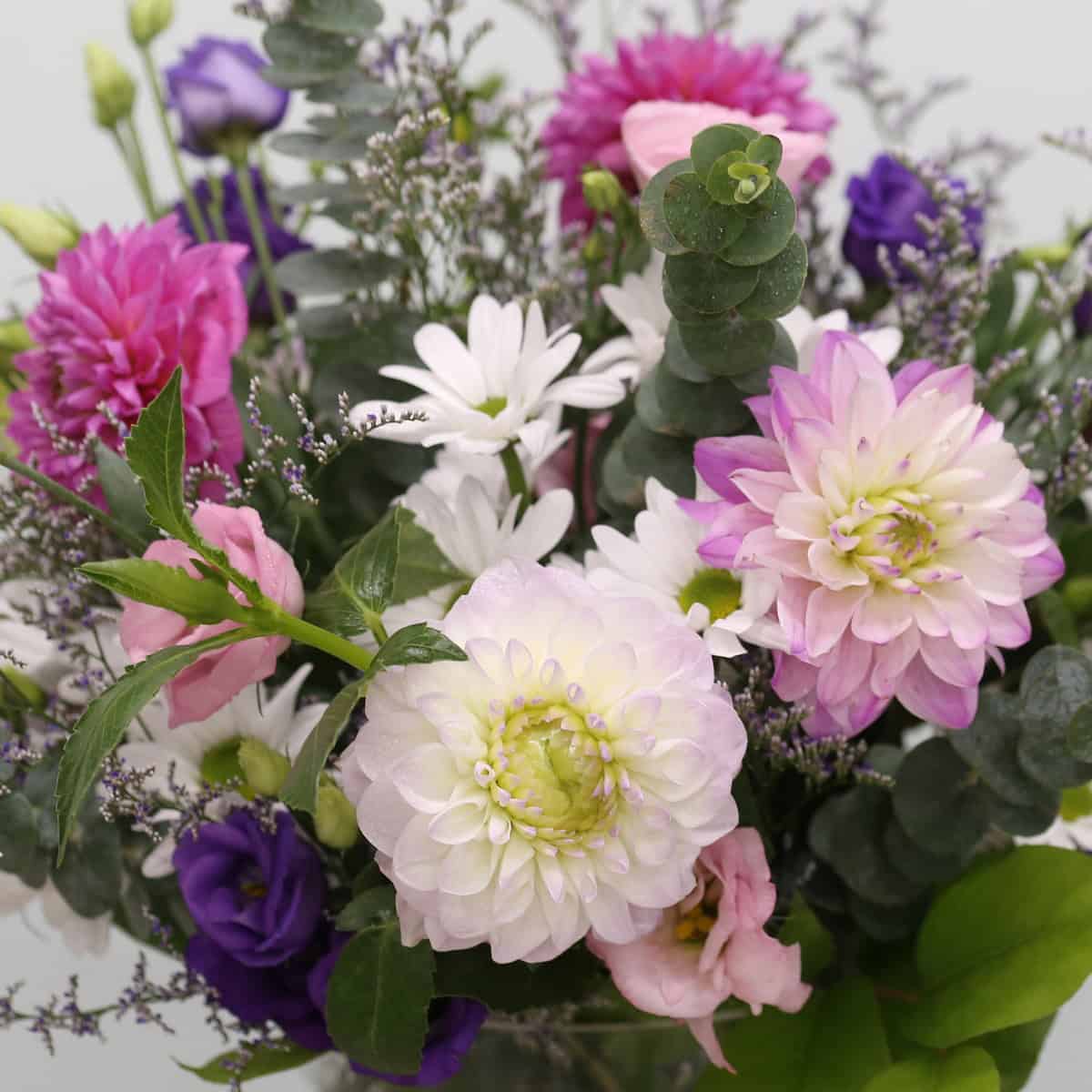Close-up of Ariana Premium Bouquet with pink dahlias, purple lisianthus, white daisies and eucalyptus