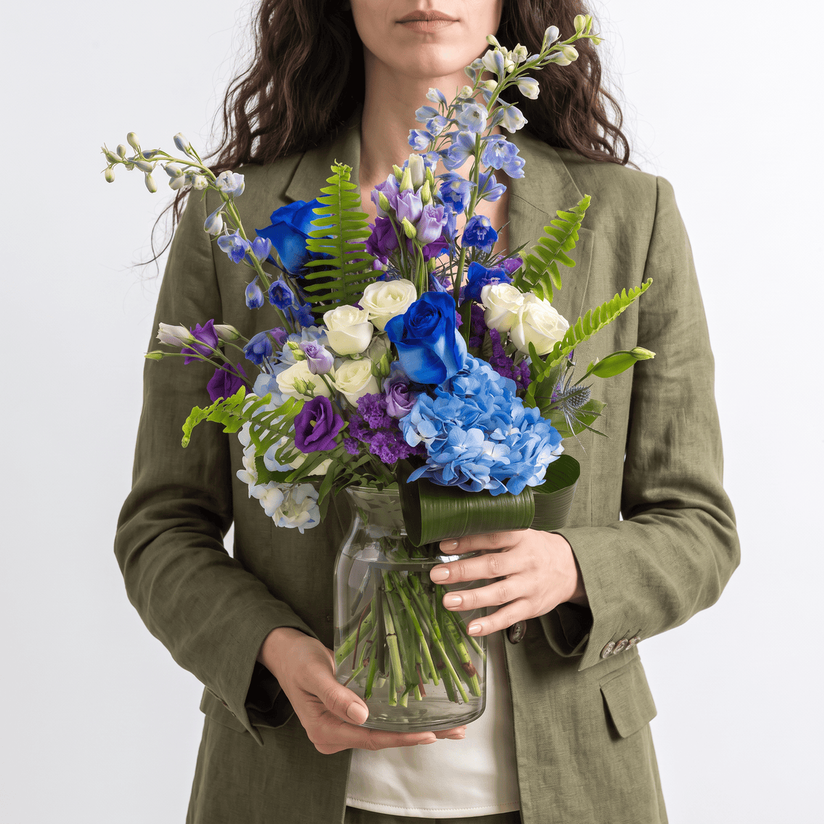 Woman holding the Blue Skies flower arrangement featuring blue hydrangea, blue roses and delphinium.