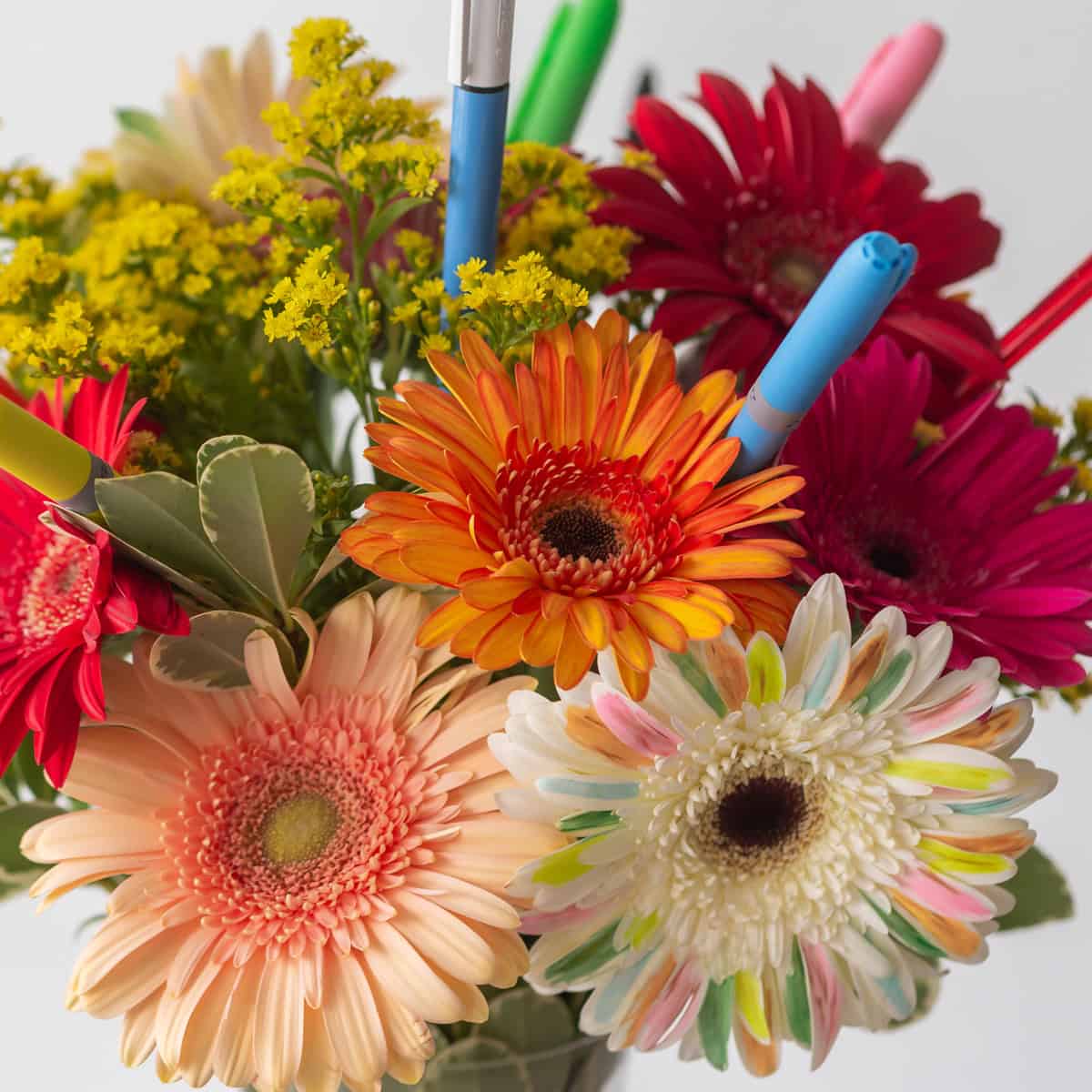 Bright Future flower detail with orange and colourful gerbera daisies, yellow solidago and pens