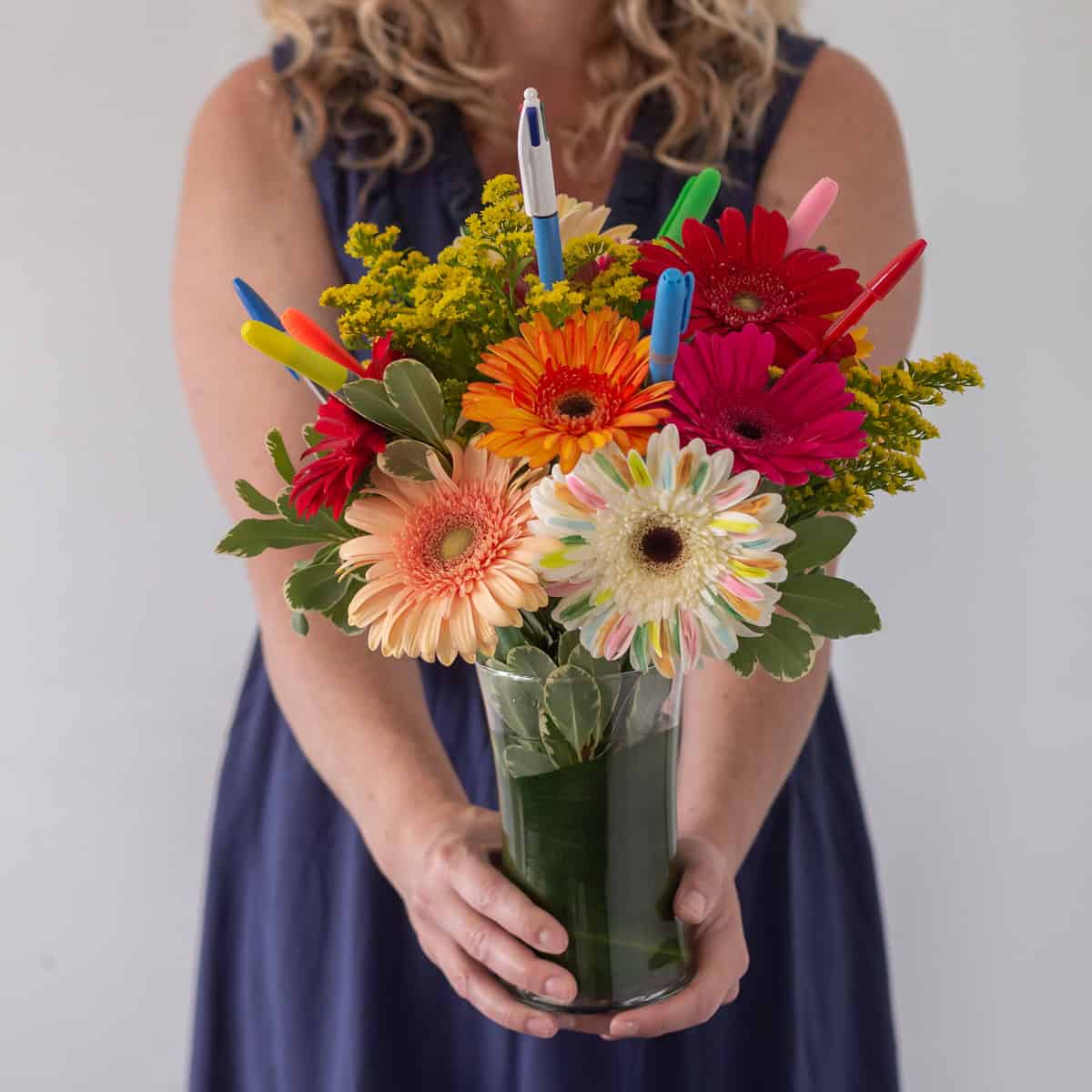 Woman holding Bright Future colourful gerbera flower arrangement with pens and highlighters