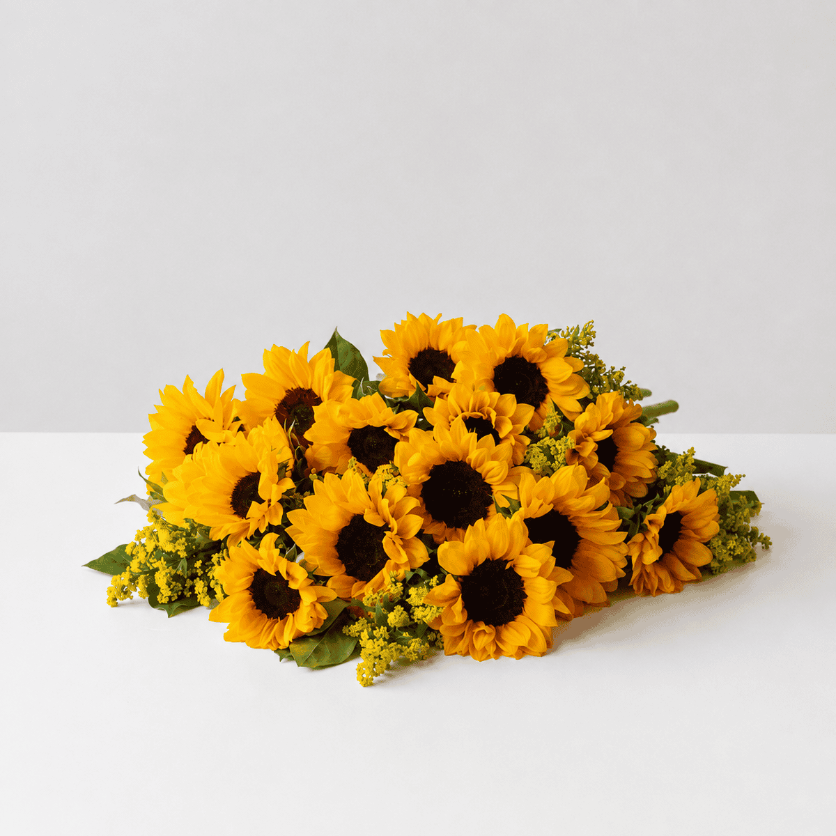 Hand-tied bouquet of fresh-cut sunflowers with solidago and seasonal greenery.