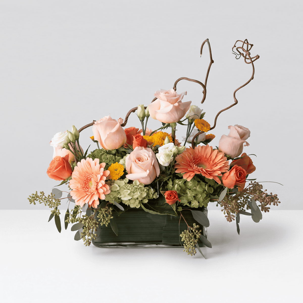 Graceful Elegance flower arrangement with peach roses, gerberas, green hydrangea and decorative curly willow branches.