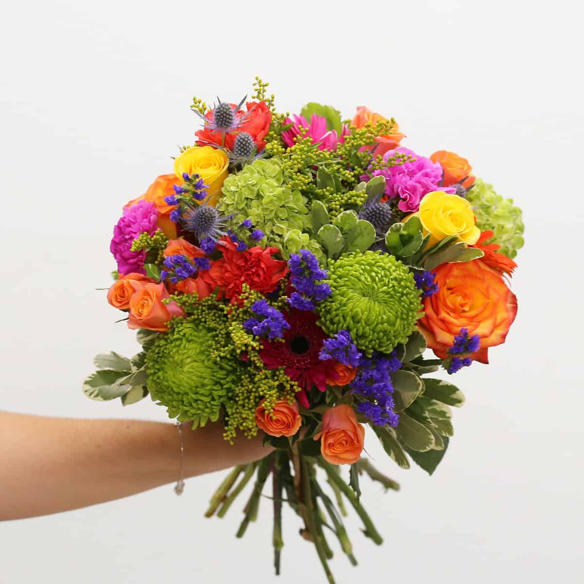 Deluxe Heatwave hand-tied bouquet with colourful roses, green hydrangea, gerbera daisies, carnations, statice and blue thistle