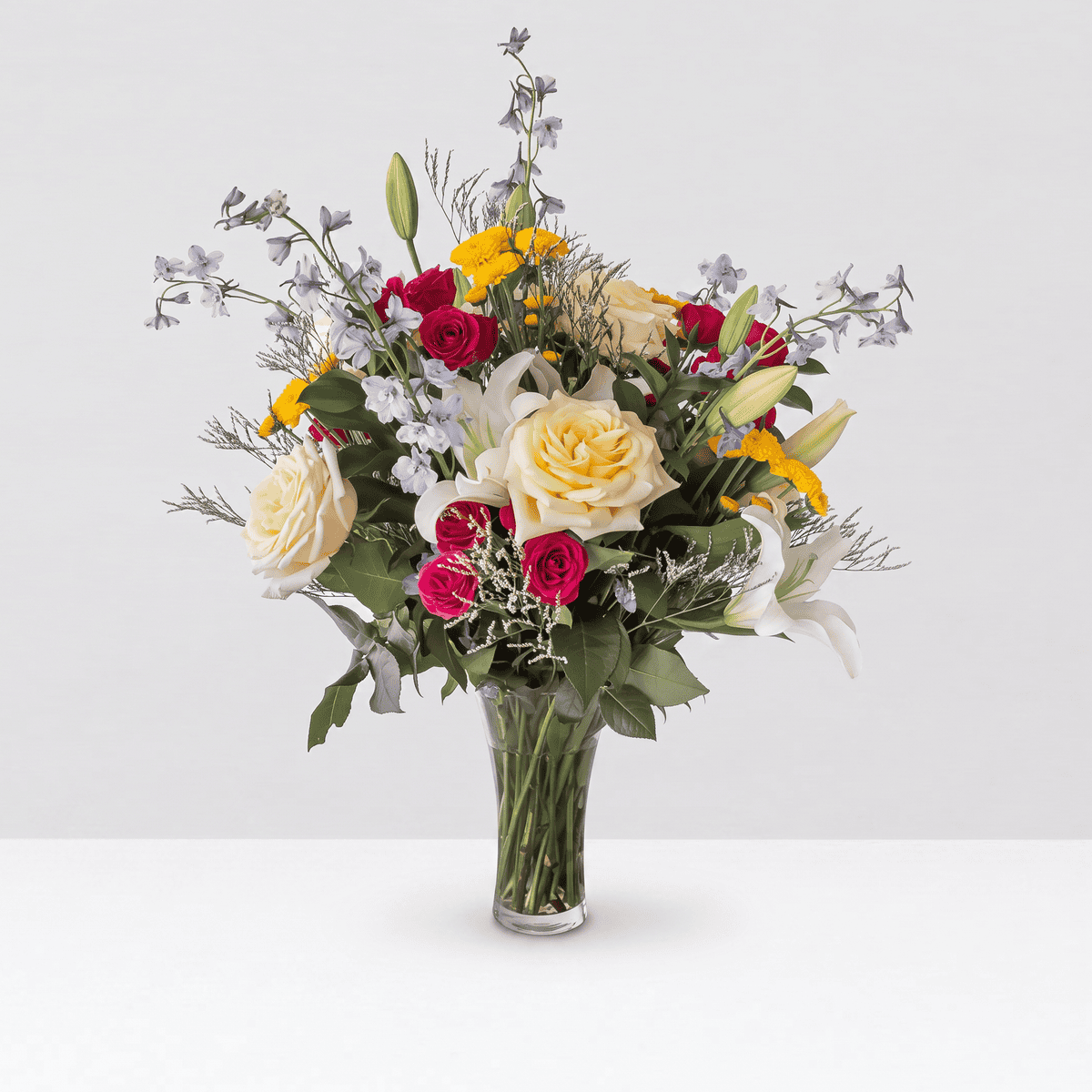 Premium New Day Dawns flower arrangement with white lilies, cream roses, fuchsia spray roses and blue delphinium