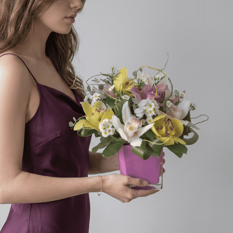 Woman holding the Orchid Symphony Cymbidium orchid arrangement.