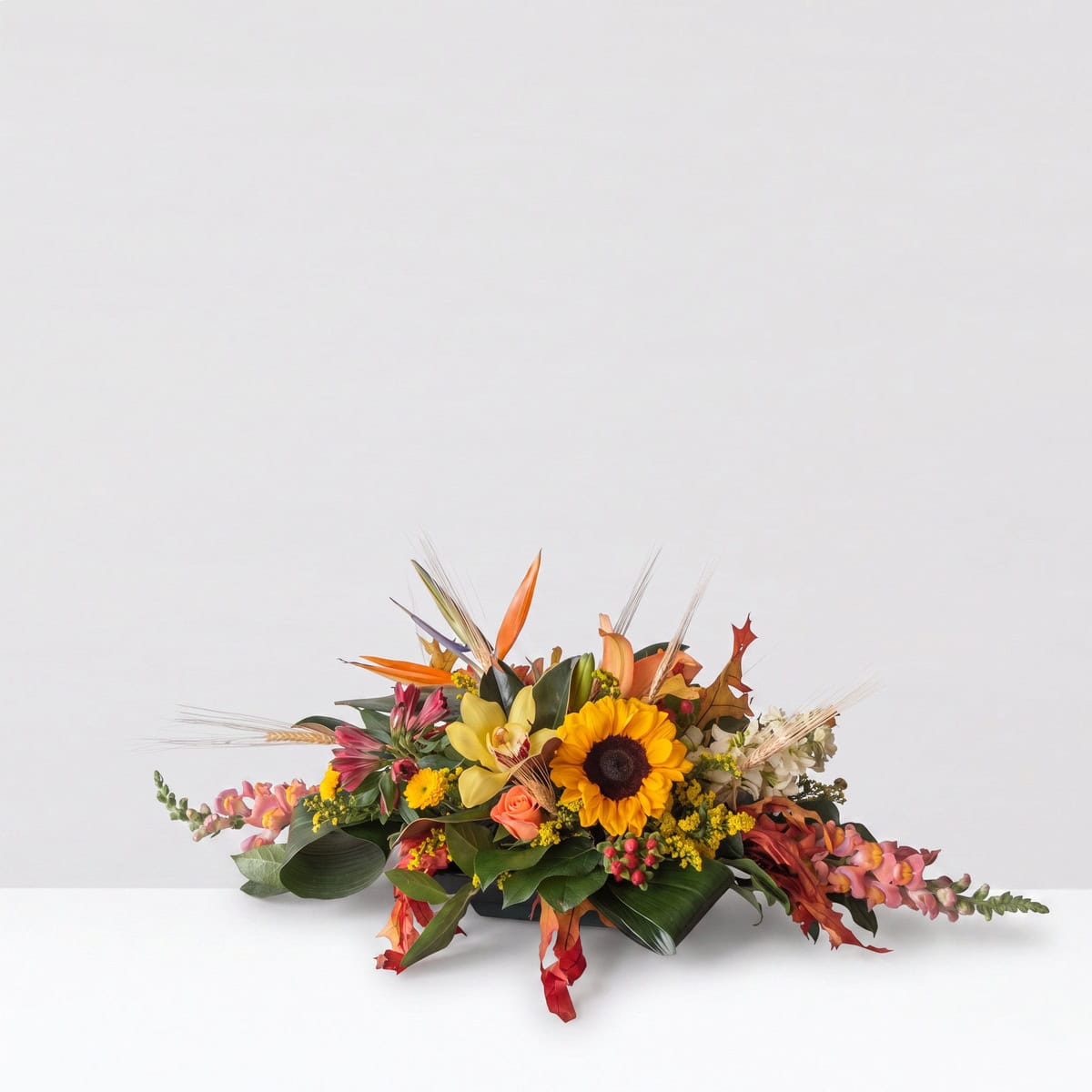 Premium Oval Centerpiece with sunflower, orchids, roses and seasonal fall flowers in red, yellow and orange