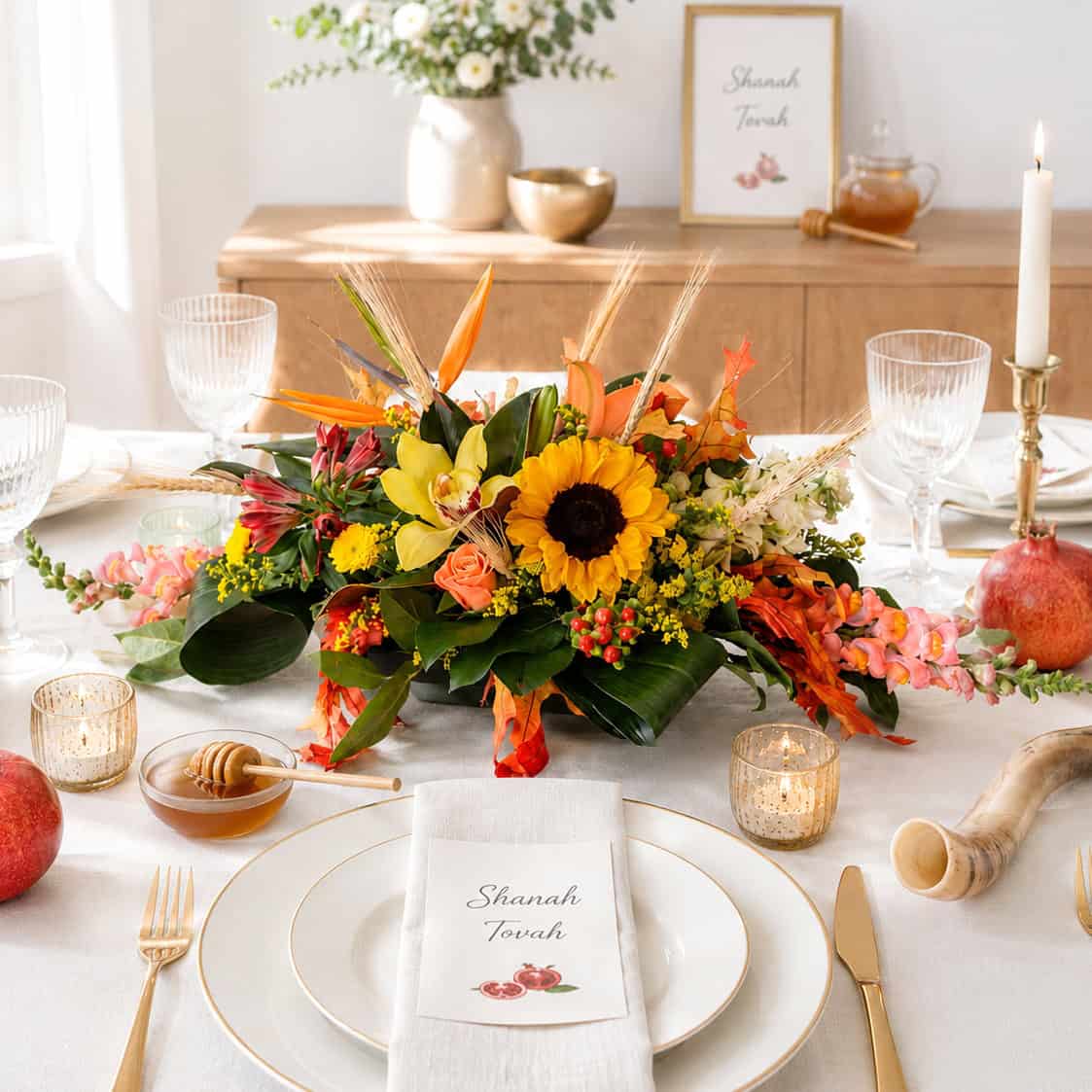 Oval floral centerpiece with sunflowers and fall flowers on an elegant Rosh Hashanah dinner table