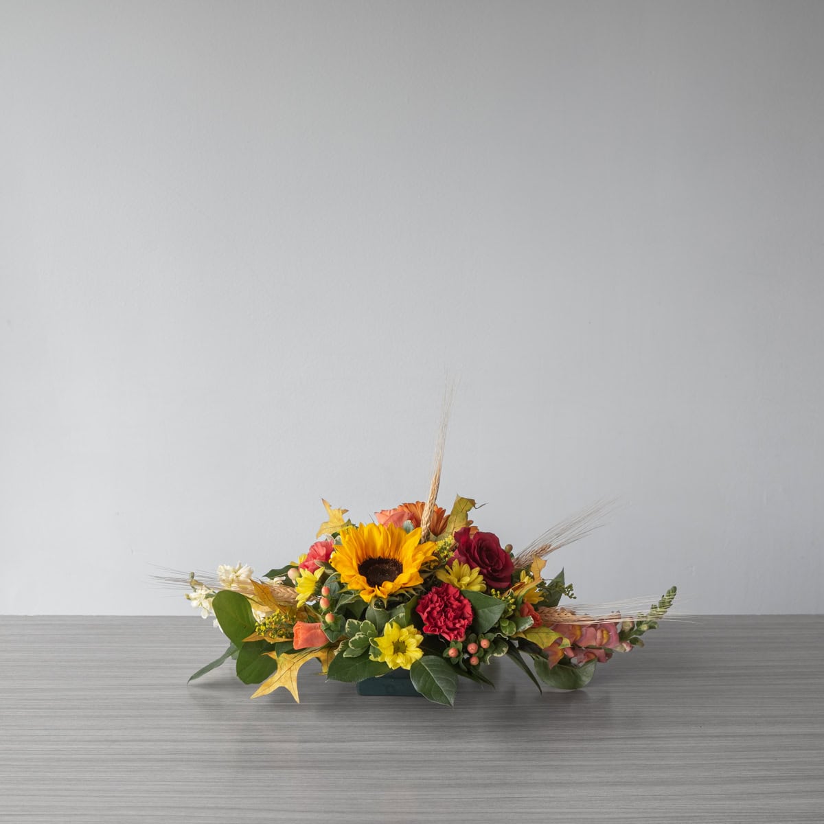 Standard Oval Centerpiece with sunflower, roses, carnations and seasonal fall flowers in red, yellow and orange
