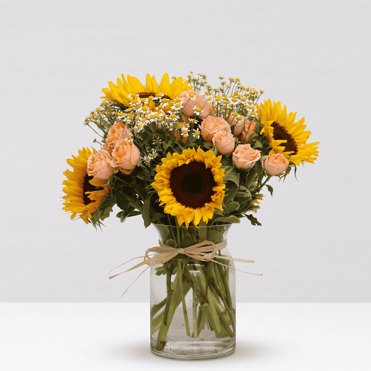 Sunrise Bouquet professionally arranged in a glass vase with sunflowers, peach spray roses and chamomile.