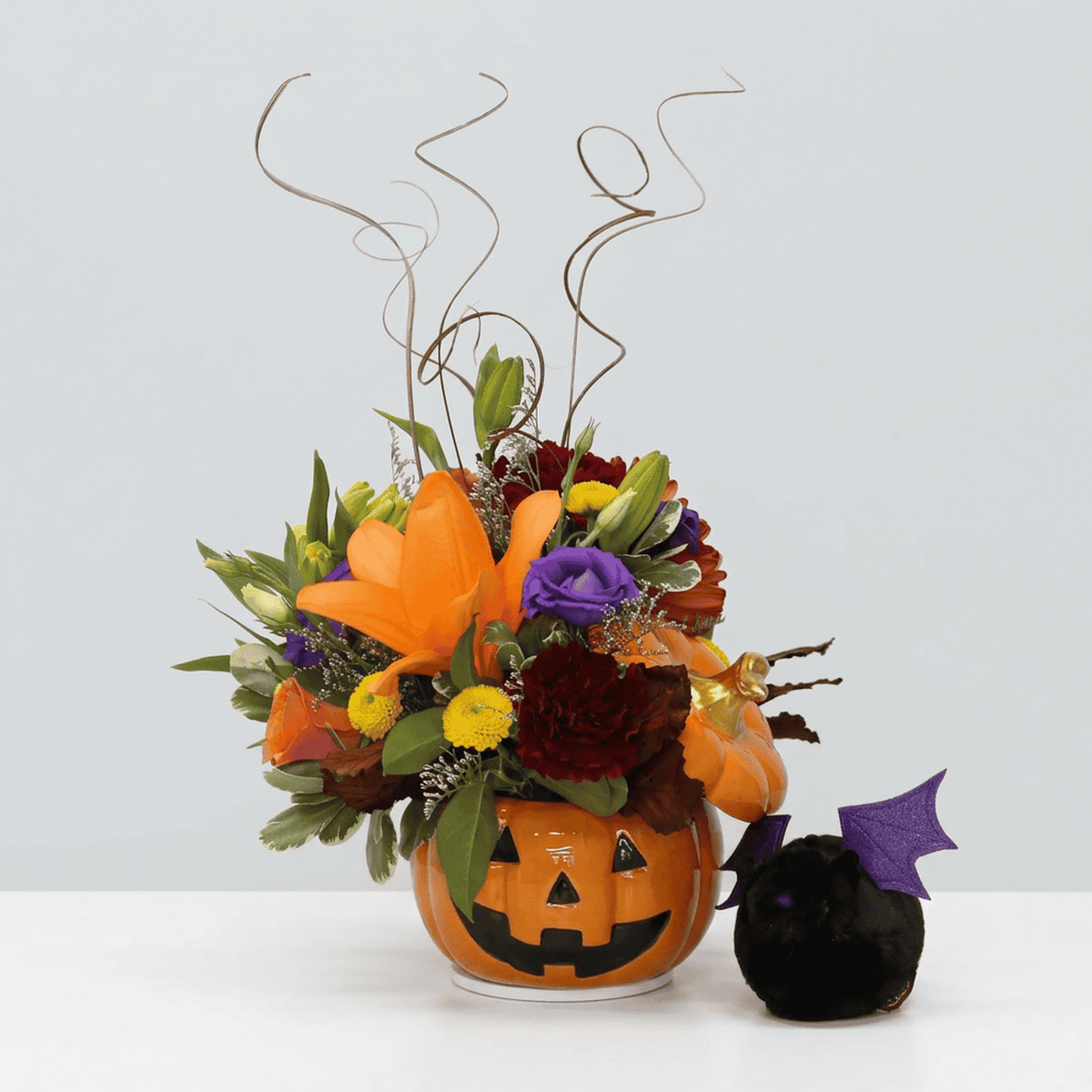 Jack and Friends Halloween flower arrangement in a ceramic pumpkin with black and purple bat plush